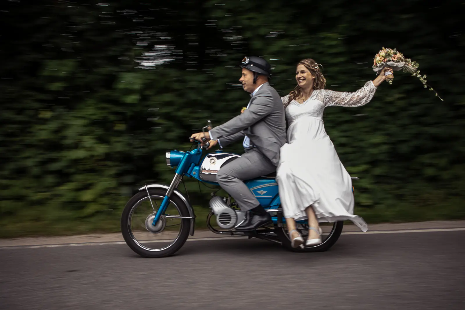 Brautpaar faehrt auf einem alten Moped und hat Spass